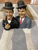 Front view of two painted bust figurines of Laurel & Hardy, showing detailed facial expressions and clothing.