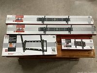 Four boxes of Barkan TV wall mounts displayed on a wooden surface, showing front packaging views of the mounts.