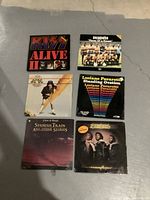 Photo of 6 records laid on floor with visible front covers showing different artist album art.