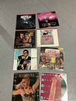 Photo showing seven LaserDiscs arranged on a grey floor, featuring movies and concerts with clear cover art.