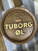Round wooden Tuborg Øl tavern bar sign with golden lettering and crown.