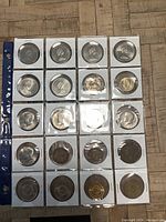 Sheet holding 24 circulated coins in individual coin holders, majority appears to be Canadian and USA coins.