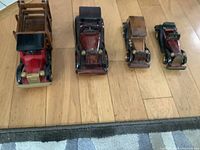 Front view of four wooden vintage car models arranged in a row on wooden flooring