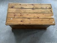 Top view of wooden treasure box showing wood plank construction, natural finish, and surface scratches.