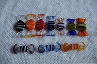 Full view of 10 colorful Murano glass candy pieces arranged on white fabric.