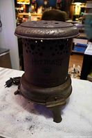 Side view of antique Hot Blast electric heater showing cylindrical body with ventilation holes and front key.