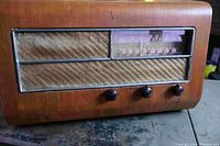 Front view of the 1946 GLF tube radio showing wooden cabinet, fabric speaker grille, tuning window, and control knobs.
