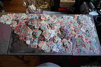 Wide overhead view showing a large scattered quantity of various used postage stamps spread out on a surface.