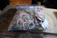 Large plastic bag filled with assorted postage stamps from various countries, showing a mix of colors and sizes.