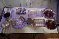 Photo showing the full assortment of the lot, including serving trays, plates with wooden inserts, a small bucket, and an ornate basket with handle.