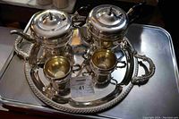 Full tea set with two teapots, two cups on large silver tray shown from overhead angle