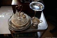 Photo showing full lot on metal cart with trays, lazy Susan set, creamer, and compote dish