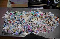 Wide spread of thousands of assorted postage stamps laid out on a table showing variety of designs and colors.