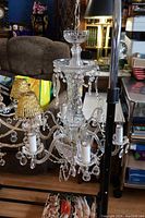 Full view of the large vintage crystal chandelier showing multiple arms with glass beads and candle-like bulbs, suspended from a chain.