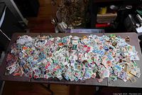 Large spread of thousands of mixed postage stamps with various colors and designs laid out on a table