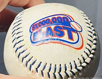 Close-up photo of a white baseball featuring a colorful "$1,000,000 Blast" logo printed on it.
