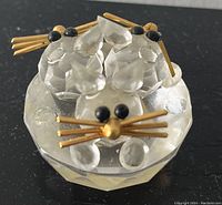 Two Bohemian crystal cat figurines with black eyes and gold whiskers, placed on a faceted crystal base.