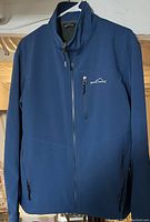 Full view of men's blue softshell jacket with front zipper and pockets