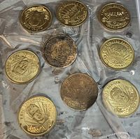 Photo showing 9 hockey coins laid out on a plastic surface, including gold and silver-tone coins with player portraits and team logos