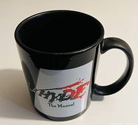 Side of mug showing Hyde The Musical logo with red splatter design on black ceramic