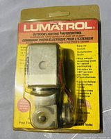 Lumatrol outdoor lighting photocontrol in original blister packaging with visible mounting hardware and installation wiring.