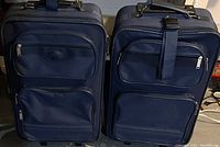 Pair of blue soft-sided suitcases side by side showing front pockets and handles