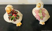 Front view of the pair of ceramic duck figurines with fabric bows and floral decorations
