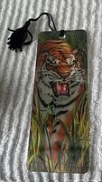 Photo of a rectangular bookmark showing a detailed tiger image with a black tassel