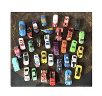 Top view photo showing 34 assorted diecast toy cars and one helicopter, highlighting variety of colors and models.