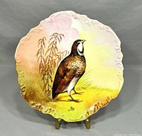 Full view of the antique Limoges decorative plate showing scalloped edges, hand-painted bird, and embossed floral rim.