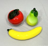 Overall view of three art glass fruit figurines on neutral background.