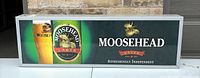 Front view of Moosehead Lager electric lighted sign showing the illuminated bottle, glass, moose logo, and brand text.