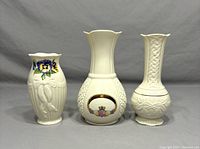Front view of three vintage Belleek Ireland porcelain vases showing different designs and heights