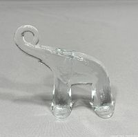 Side view of clear glass elephant figurine showing curled trunk and legs