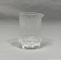 Front and side view of the clear glass creamer jug showing the textured surface and pour spout.