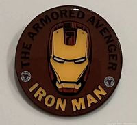 Front of the Iron Man collector's pin showing the helmet and text.