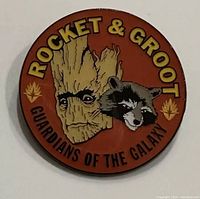 Front view of the collectible enamel pin showcasing Rocket and Groot with Guardians of the Galaxy text on an orange background.
