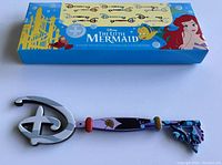 Collector key themed on Ursula from The Little Mermaid with original packaging box in the background.
