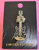Image of the Hard Rock Limited Edition Berlin Guitar shaped pin attached to its original black display card with 'LIMITED EDITION' in gold lettering.
