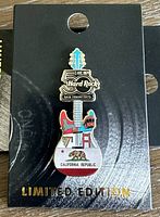 Front view of the Hard Rock San Francisco Limited Edition pin attached to its backing card showing detailed guitar design with San Francisco landmarks and California Republic text.