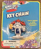 Front of original packaging showing figurine keychain of Hawaiian Punch mascot with striped shirt and orange cup.