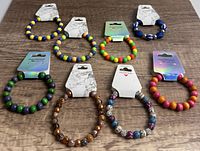 All 8 beaded bracelets shown together on wooden surface, showing variety in bead type and colors