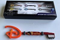Image showing the Marvel Studios The Infinity Saga collector key themed with 'I Am Iron Man' design in red and gold, with the Marvel logo tag and an orange Disney keychain. The packaging displays all collectible keys available in the series.