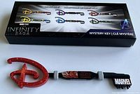 Image of a collector key in red Disney D shape with black handle labeled 'World's Greatest Grandma' and Marvel logo; packaging box showing other related collector keys.