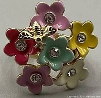 Front view of vintage gold tone adjustable ring with six multicolor enamel flowers and a gold bee accent, showing rhinestone centers