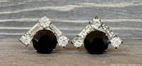 Front view of vintage sterling silver earrings showing round black stone with clear stone accents in triangular pattern.