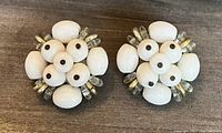 Front view of the pair of white beaded clip-on earrings showing floral bead arrangement with white and clear beads.