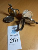 Two pocket watches laid open showing cases and removed case backs