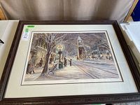 Full shot of the framed limited edition art print Candlelight Stroll showing snow-covered street with man and child by lamppost and town backdrop.