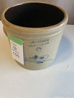 Full view of stoneware crock pot showing shape, interior, and exterior surface with label and markings.